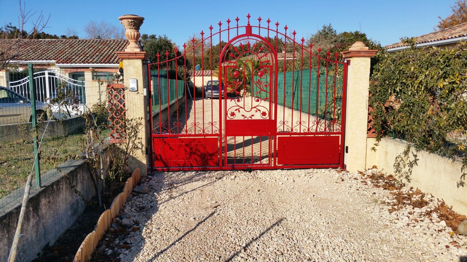 Portail battant en acier rouge motorisé avec ouverture piétonne centrale installé à Lagarde (31290) par GPA Automatisme. Sécurisation et praticité avec un accès indépendant intégré.