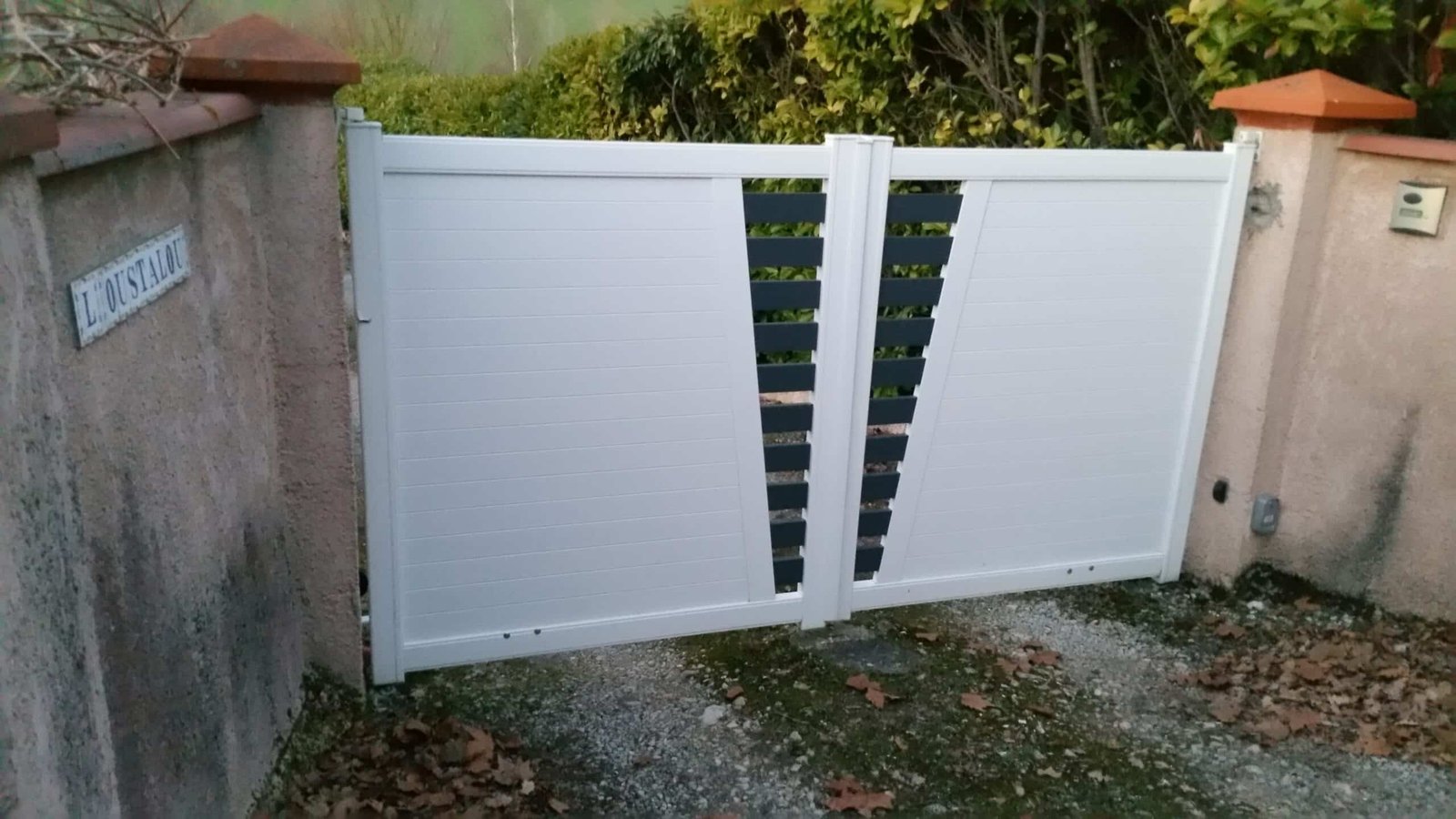 Portail battant blanc motorisé en aluminium avec ouverture centrale et ajout gris installé à Montclar-Lauragais (31290) par GPA Automatisme. Sécurisation et design moderne avec un contraste élégant