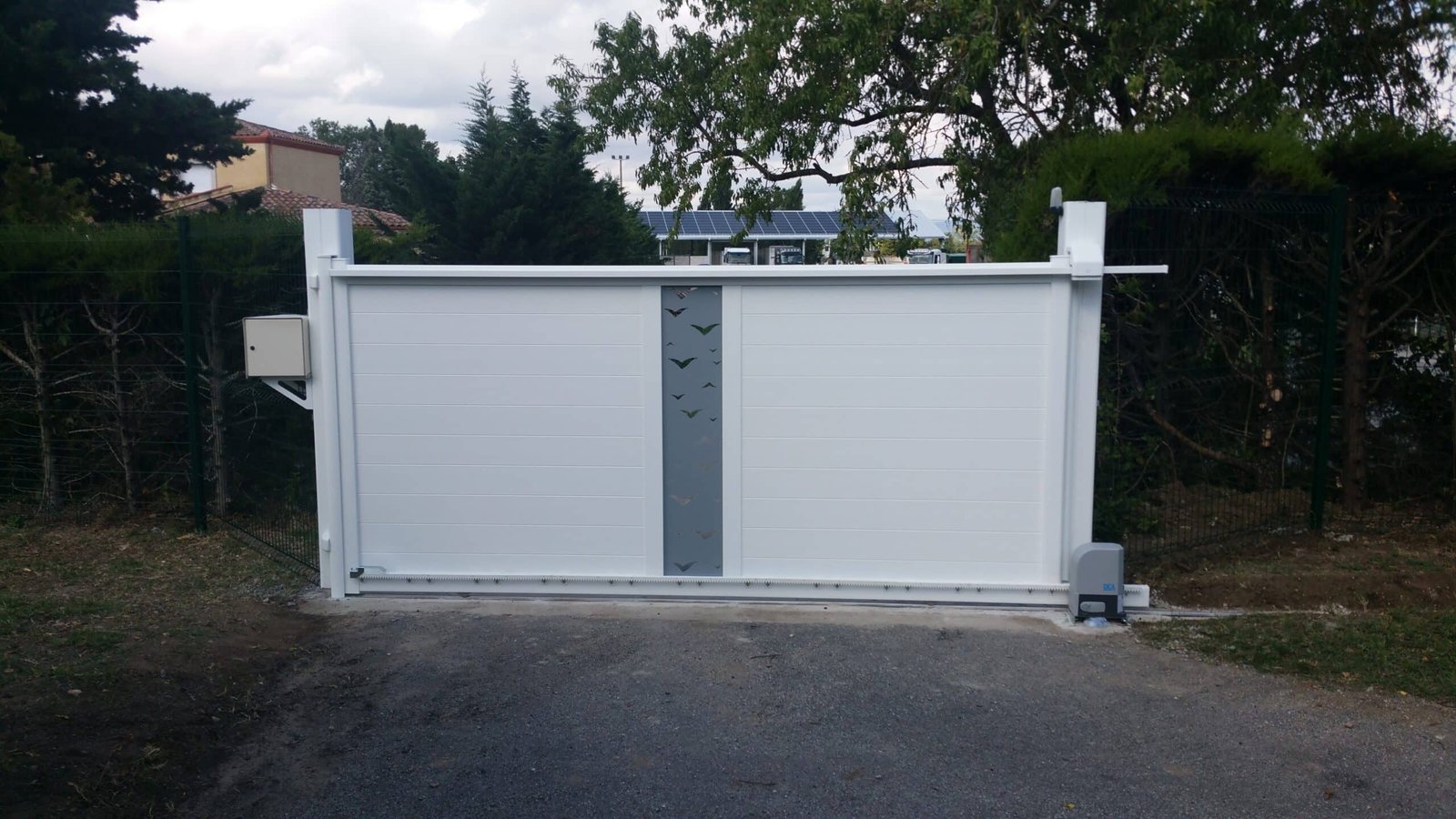 Portail coulissant blanc avec motif mouette, insert gris et motorisation installé à Caragoudes (31460) par GPA Automatisme. Élégance et personnalisation pour une entrée moderne et automatisée