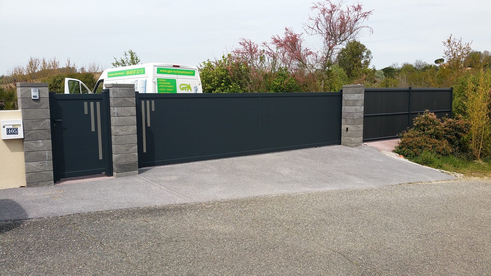 Portail motorisé avec clôture et portillon, équipé d’un portier audio et vidéo design installé à Vendine (31460) par GPA Automatisme. Sécurisation et modernité pour une entrée haut de gamme.