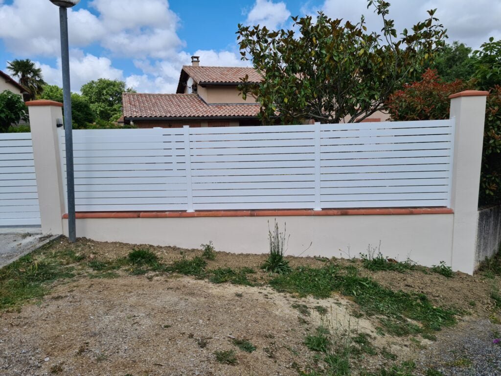 Clôture blanche et portail coulissant installés à Caraman (31460) par GPA Automatisme. Solution élégante et pratique pour une entrée moderne et sécurisée
