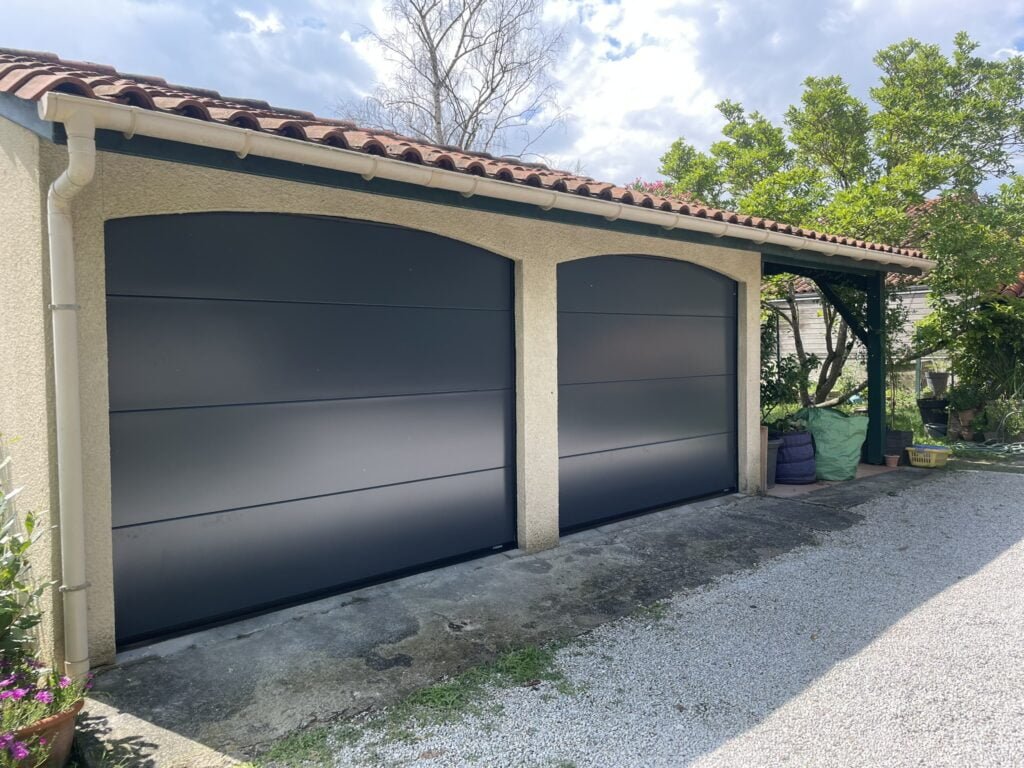 Deux portails sectionnels gris motorisés installés à Nailloux (31560) par GPA Automatisme. Sécurisation et design moderne pour deux grandes entrées pratiques et élégantes