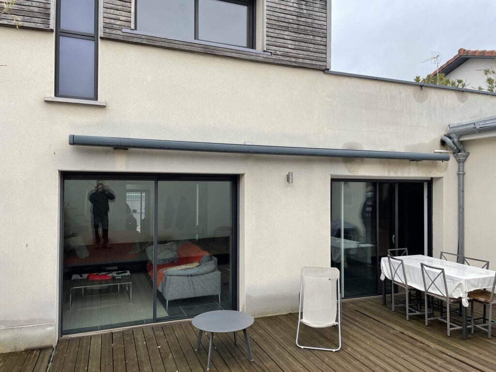 Grand store banne coffre motorisé gris avec rétraction vent installé à Caraman (31460) par GPA Automatisme. Protection solaire optimale pour de grandes surfaces extérieures