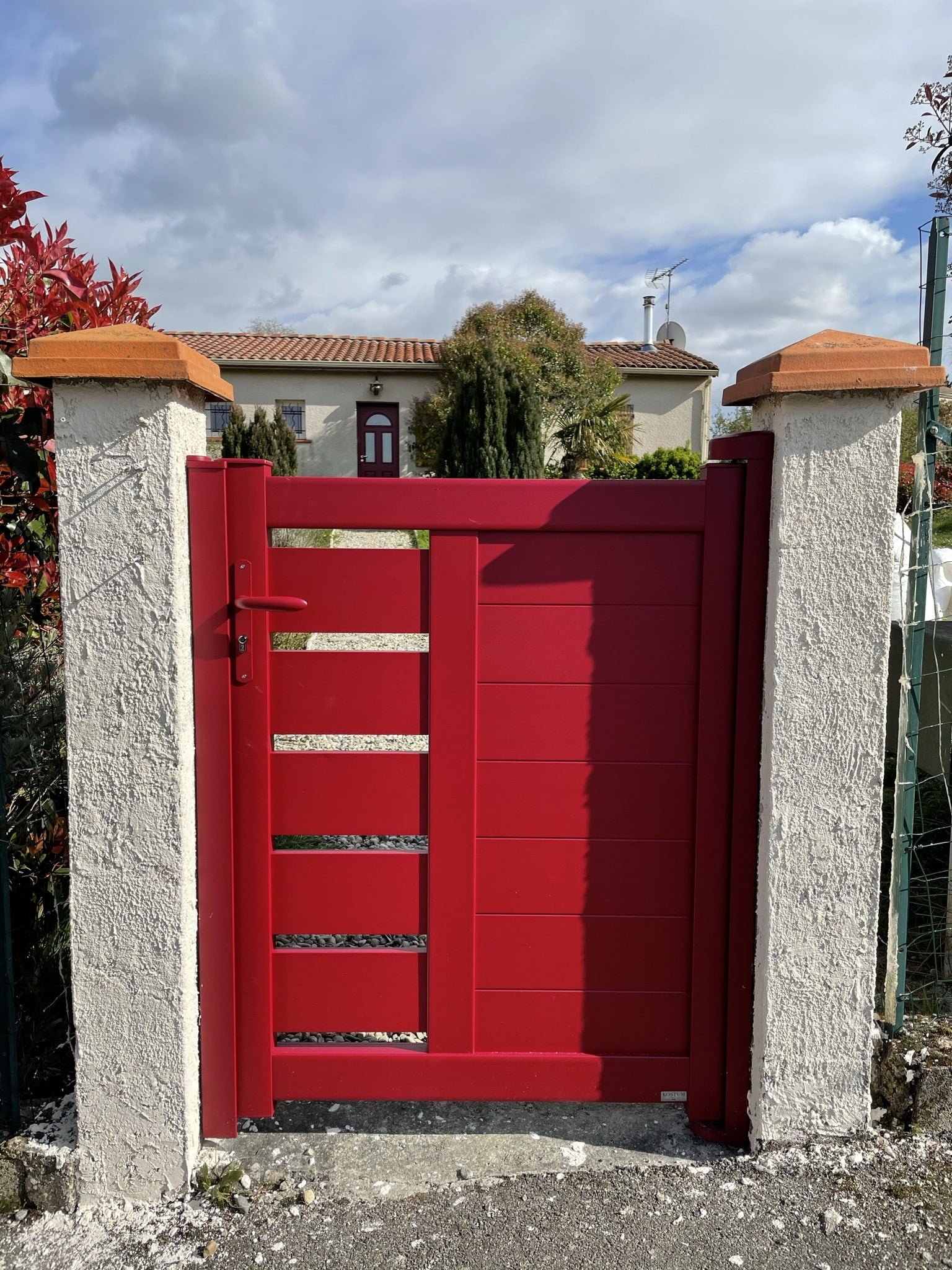 Portillon en aluminium rouge semi-ajouré installé à Loubens-Lauragais (31460) par GPA Automatisme. Design moderne et sécurité optimisée pour une entrée élégante