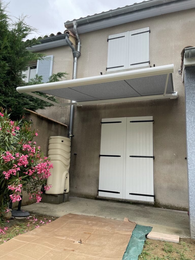 Store banne coffre motorisé gris avec rétraction vent installé à Caraman (31460) par GPA Automatisme. Protection solaire avec rétraction automatique en cas de vent pour une entrée élégante et sécurisée