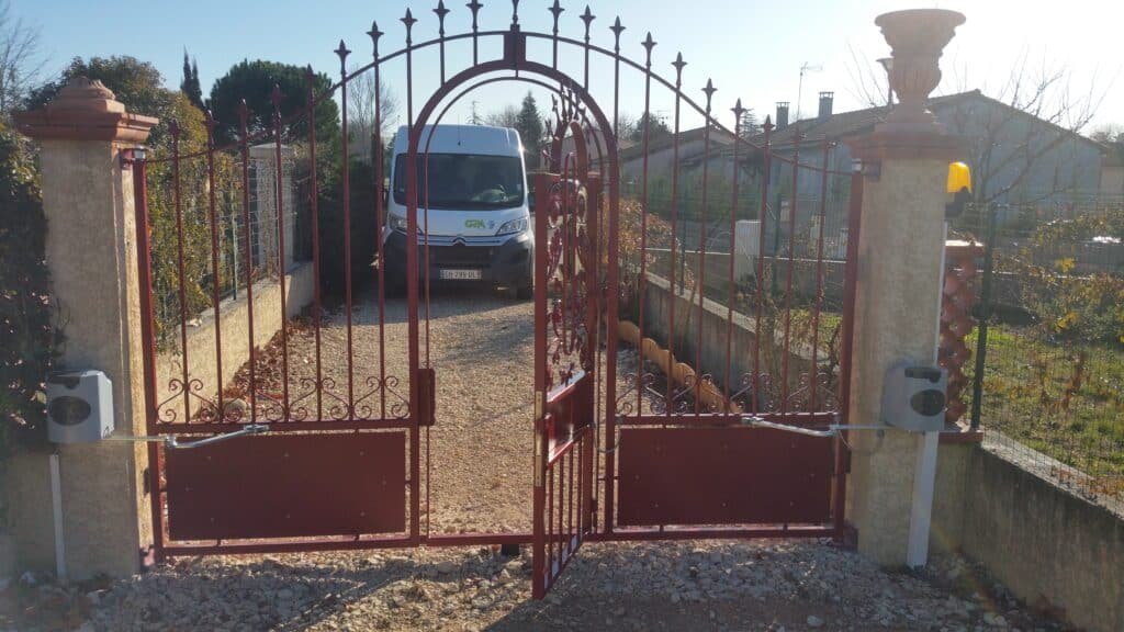 Portail battant rouge thermolaqué avec ouverture piétonne centrale installé à Caraman (31460) par GPA Automatisme. Pose et motorisation de portails sur mesure dans tout le Lauragais.